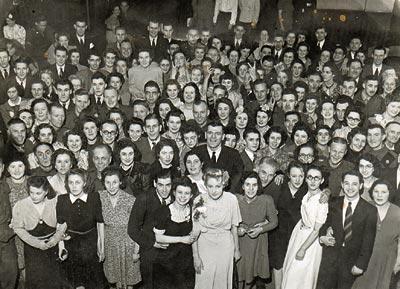 black and white photo of a lot of couples at a dance all dressed up in the 1950s.
