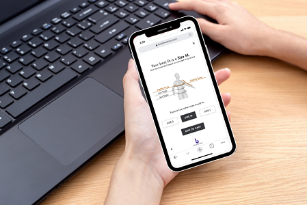 Mobile online shopping experience with Bold Metrics size recommendation feature on a smartphone held by a user.